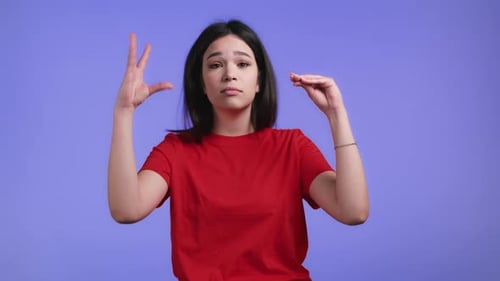 Woman Gesturing Size and Speaking on Plain Backdrop
