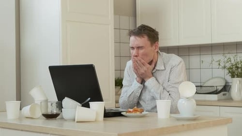 Adult Uses Laptop at Messy Kitchen Table