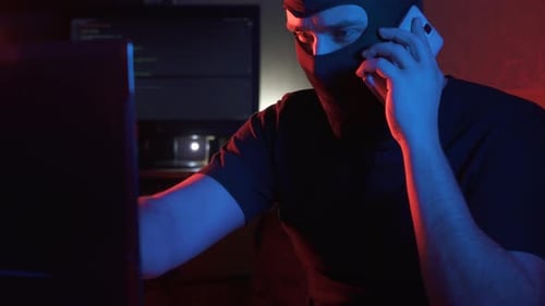 ein anonymer Mann in einer Sturmhaube kommuniziert per Telefon