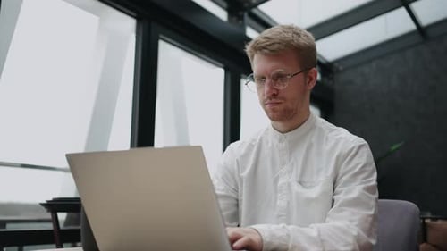 Serious Busy Businessman is Working with Laptop in His Modern Office Typing Email and Sending