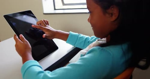Schoolgirl using digital tablet in classroom at school