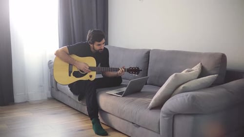 Man Plays Guitar on Couch at Home