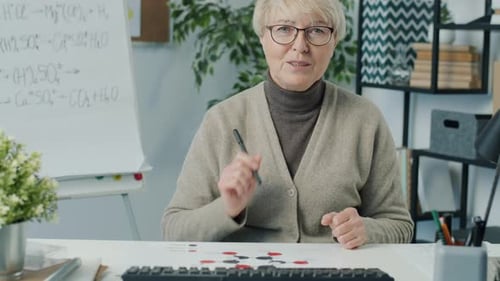Woman Explains Chemistry Lesson at Desk