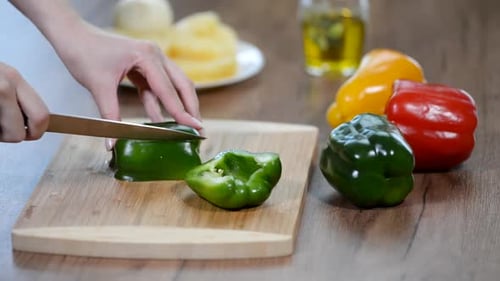 Women's hands cut green pepper on a wooden Board