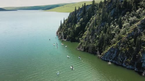 People Ride on SUP Board in the Mountain Lake