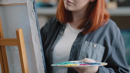 Young Artist Painting with Brush in Studio