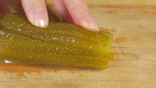 Chef Slicing Pickle on Wood Cutting Board