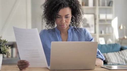 Woman Works from Home with Laptop and Paperwork