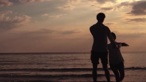 Happy asian couple walking or running and holding hand spin with romantic on the beach.
