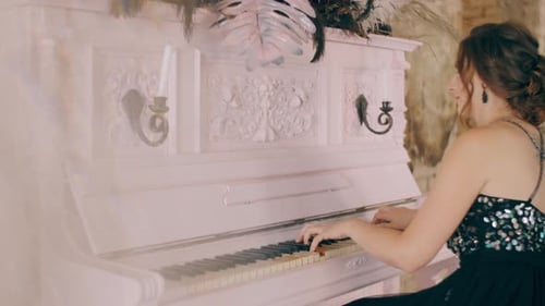 Woman Playing Piano in Room with exposed brick