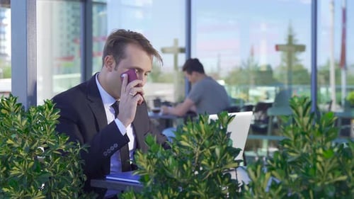 Businessman talking by phone in cafe.