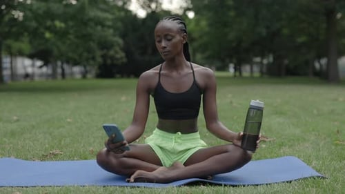 Woman Sitting Cross-Legged in Yoga Pose Checking Phone