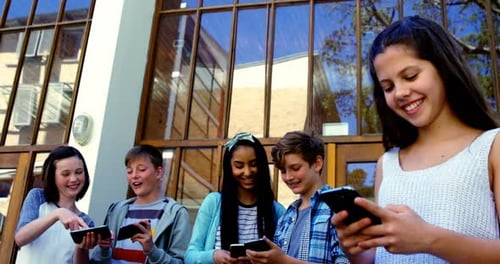 Group of school friends using mobile phone outside school