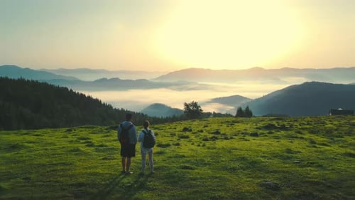 Man and Woman Meet the Sunrise on Top of the Mountain