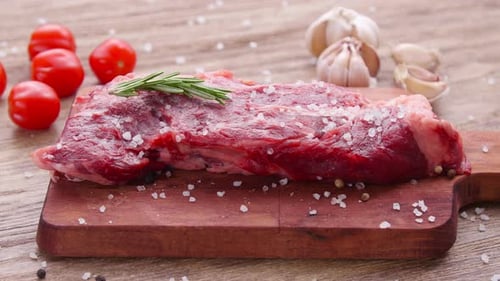 Raw Steak with Rosemary on Cutting Board