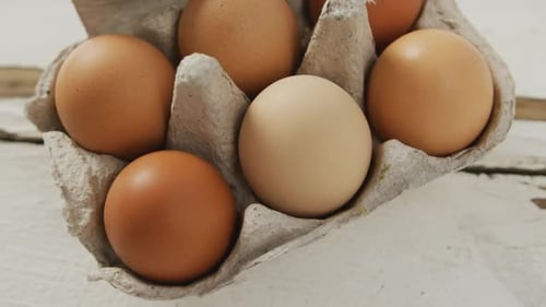 Video of close up of brown eggs in egg carton on rustic background