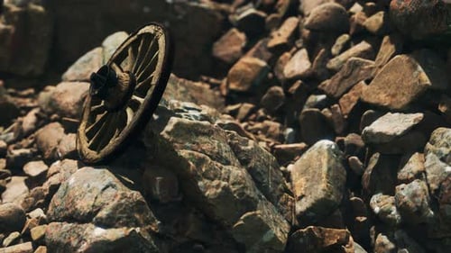 Abandoned Wooden Wagon Wheel Resting on Rocky Terrain