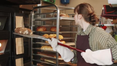 Female Baker Taking Hot Bread from Oven with Shovel