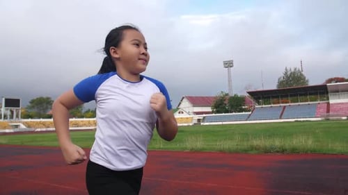 Asiatisches kleines Mädchen läuft im Stadion