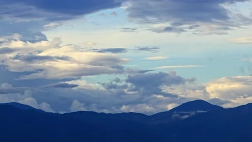 Timelapse Clouds Swirl Over Blue Mountains Snowy Peak in the Distance