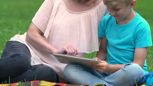 Woman and Boy Enjoying Tablet Together in Park