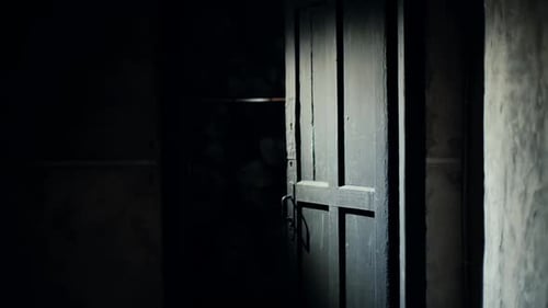 Un clown effrayant avec un sourire fou apparaît soudainement à la porte d'une pièce sombre