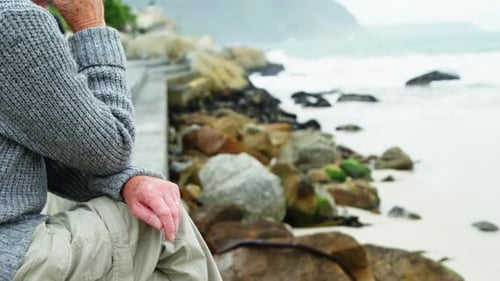 Senior Mann sitzt am Strand