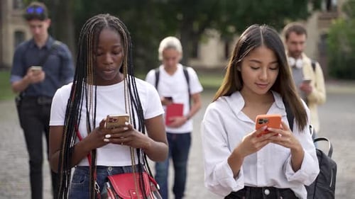 Estudiantes multirraciales que usan teléfonos celulares durante la caminata