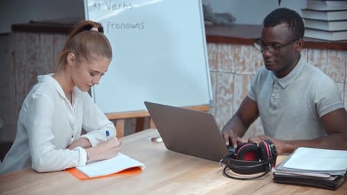 Leçon d'anglais - Une femme et un homme afro-américain ayant un cours d'anglais - Homme assis