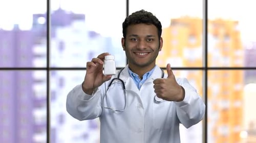 Smiling Doctor Holding Pill Bottle Gives Thumbs Up