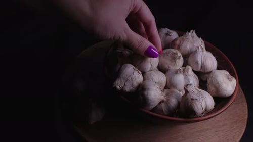 Hand Picking Garlic Cloves from Bowl