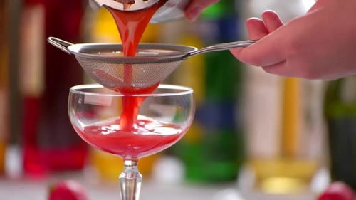 Straining Red Cocktail into Glass Close Up