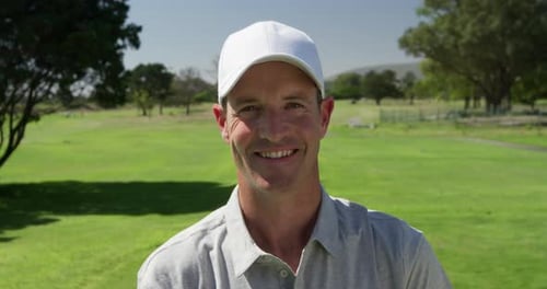 Caucasian male golfer smiling at camera on a golf course