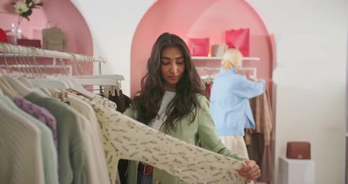 Pretty Young Brunette Woman Choosing Clothes in a Clothing Store
