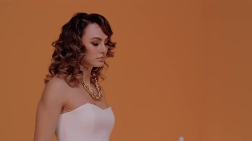 Woman in Dress Poses on Orange Background