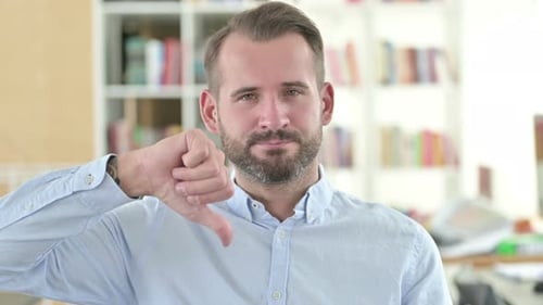 Portrait of Disappointed Young Man with Thumbs Down