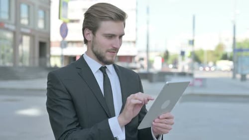 Excited Businessman Using Tablet Device Outdoors