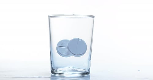 900059 Tablets, die vor weißem Hintergrund in ein Glas fallen, Zeitlupe 4K