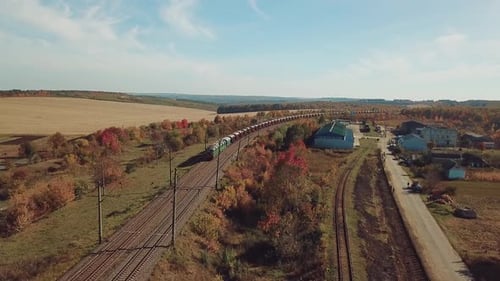 freight train is moving by rail to the nearest town on the background of the countryside
