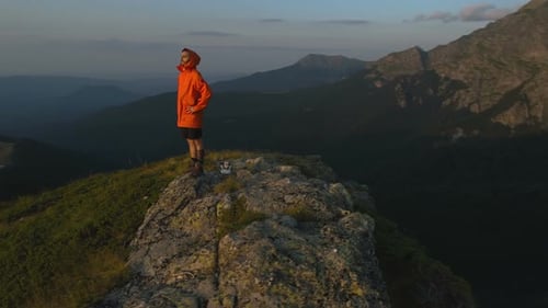 Male Tourist with Hand Above Eyes Looking Out Over a Colorful Sunset on a Mountain Range in Bulgaria