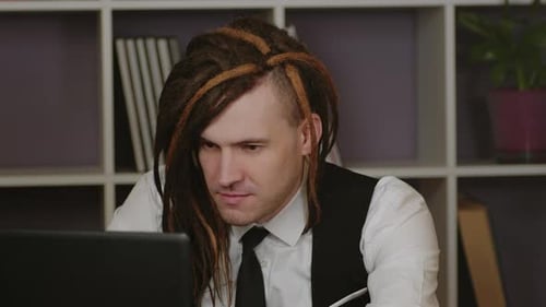 Young Man Works on Laptop Sitting in Home Office