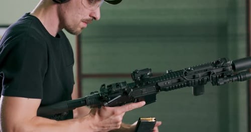 Man Inserts Magazine into a Black Rifle