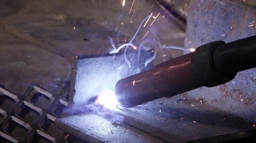 Close view of arc welder sparking as sparks shoot around.