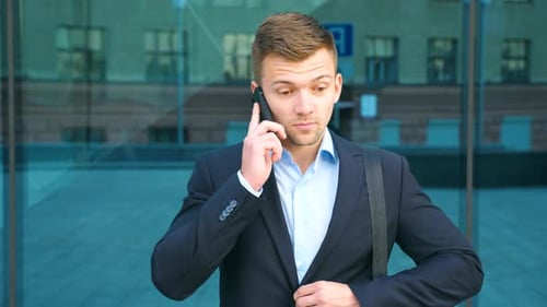 Young Businessman Talking on Phone Near Office and Celebrating Achievement