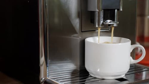 Coffee Pours Into Cup From Modern Coffee Machine in Room