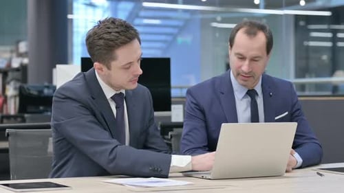 Two Businessmen Working Together at Desk with Laptop