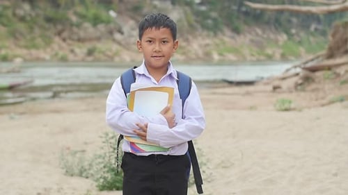 Boy in School Uniform on Riverbed Holds Books