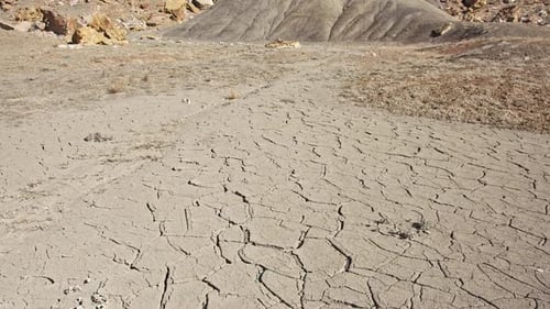 Dry cracked soil at the base of a cliff in the desert
