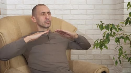 Man Practicing Breathing Exercise in Armchair