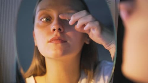 Woman Examining Her Face in the Mirror